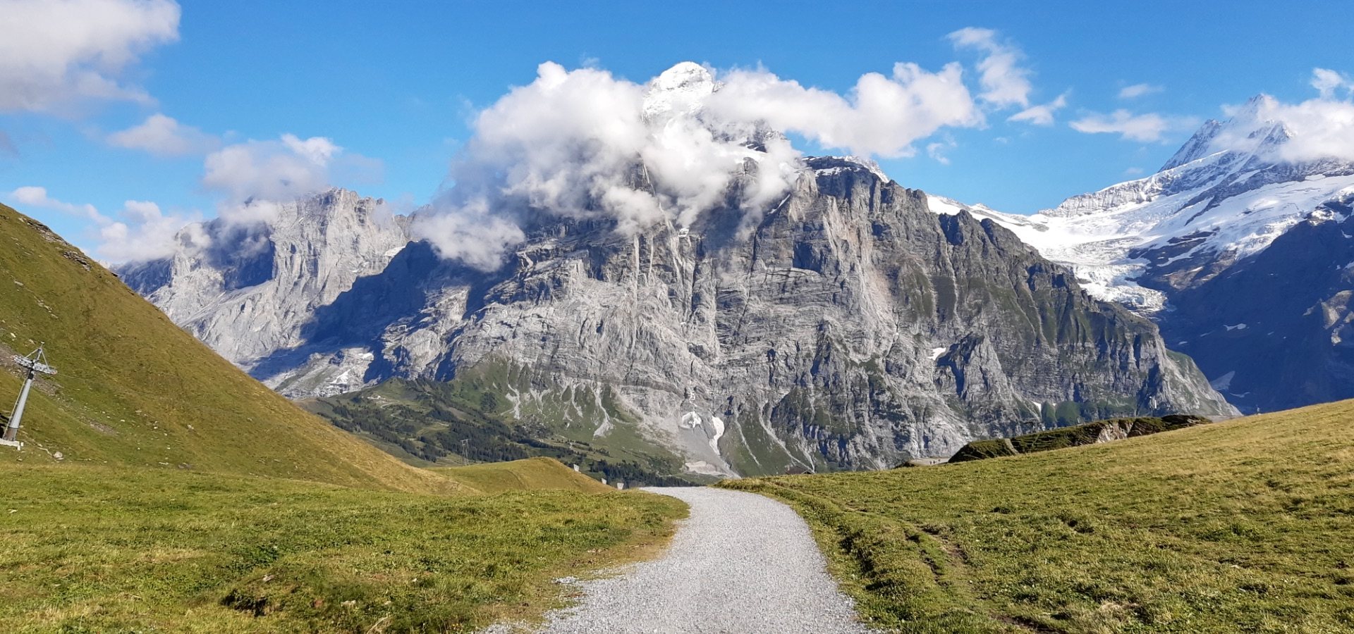 Mountain path leading towards snow-capped Swiss Alps