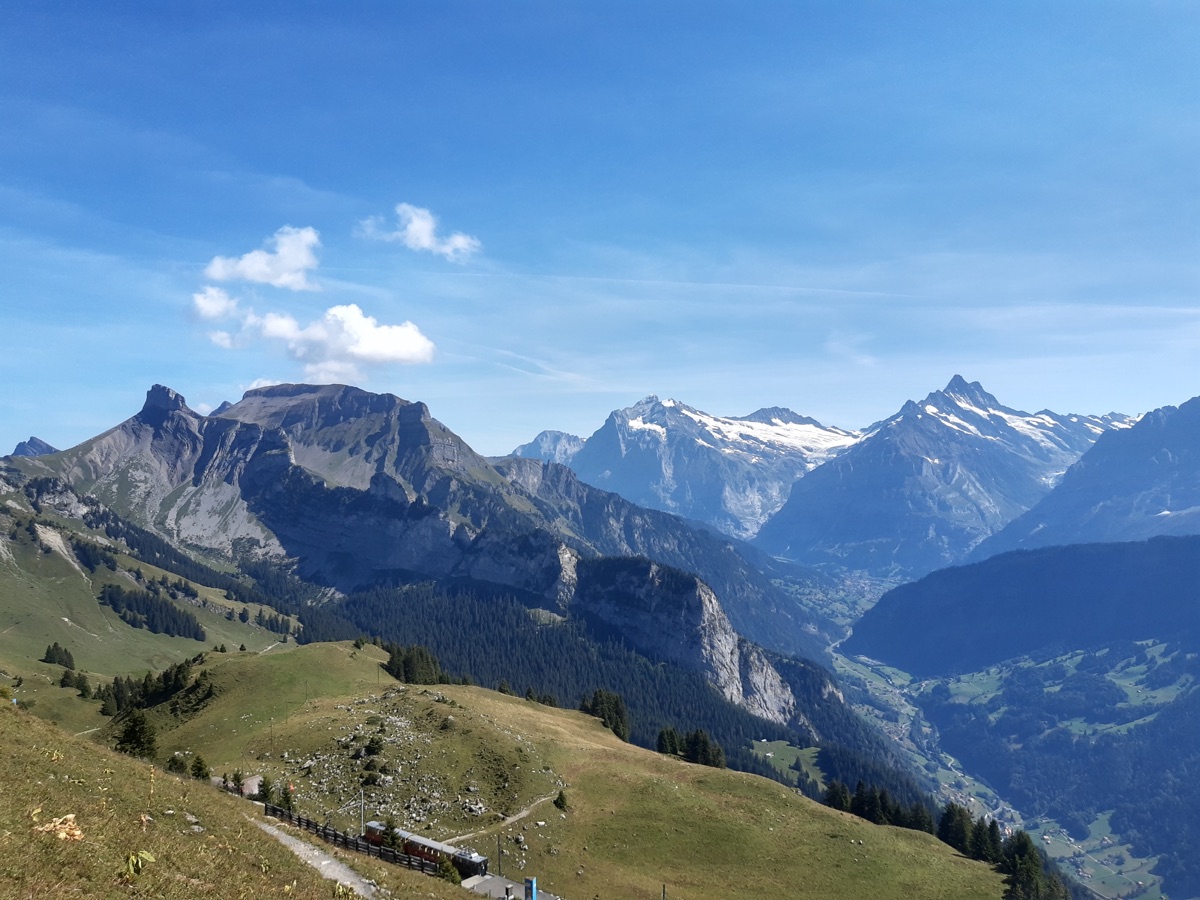 Swiss Alpine valley with a mountain railway climbing a green ridge